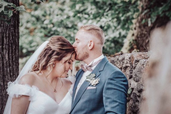 Braut und Bräutigam in Hochzeitskleidung, umarmt und glücklich in der Natur.