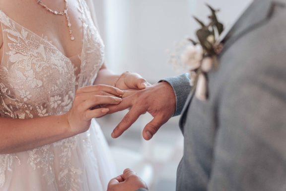 Hochzeitsszenen: Braut steckt dem Bräutigam den Ring an.