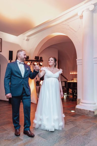 Hochzeitspaar tanzt in eleganter Umgebung. Braut in weißem Kleid, Bräutigam in Anzug.