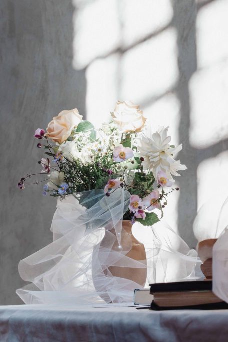 Ein Blumenstrauß in einer Vase mit weich gefiltertem Licht und einer zarten Schleife.
