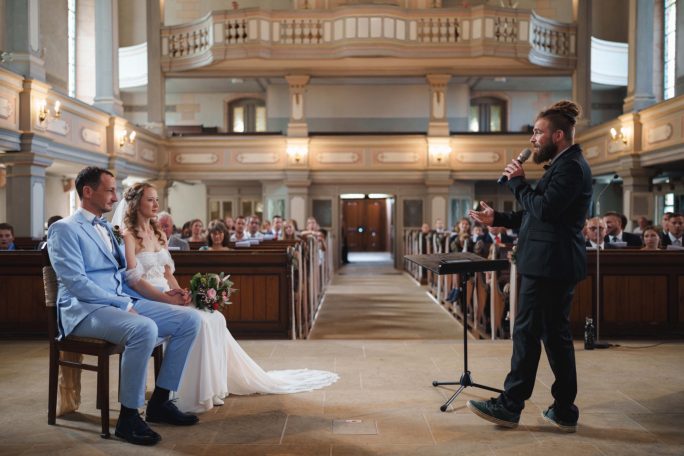 Hochzeitszeremonie in einer Kirche mit dem Brautpaar und einem Redner.