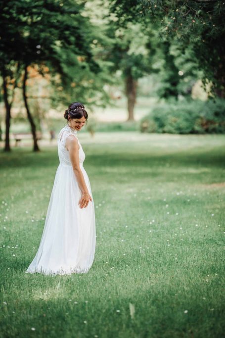 Frau in einem weißen Kleid, die im grünen Park umhergeht.