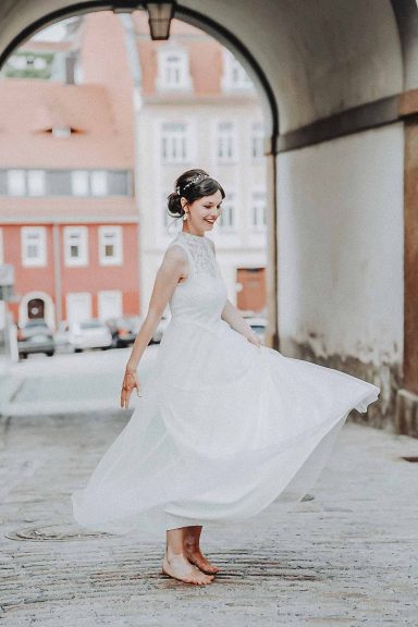 Frau in einem weißen Kleid, die in einem Bogen fröhlich umherwirbelt.