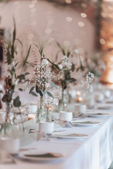 Elegante Tischdekoration mit Blumenarrangements und Kerzen in einem festlichen Ambiente.