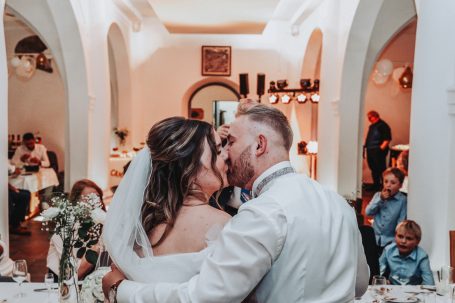 Brautpaar küsst sich im festlich dekorierten Saal während der Hochzeit.