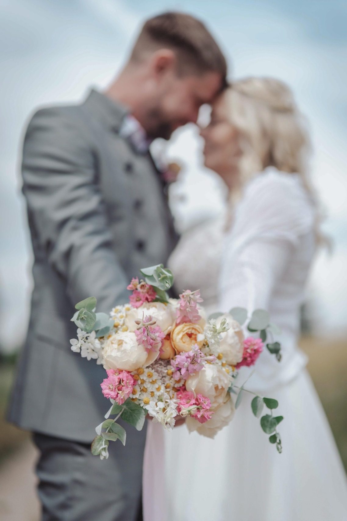 Brautpaar, das sich umarmt, mit einem Blumenstrauß und liebevollem Blick zueinander.