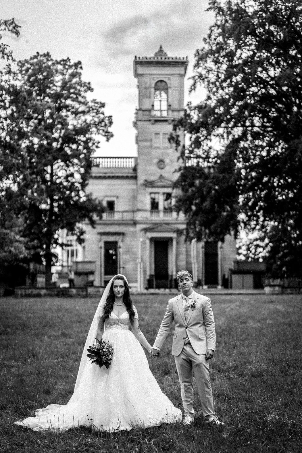 Brautpaar, das sich umarmt, mit einem Blumenstrauß und liebevollem Blick zueinander.