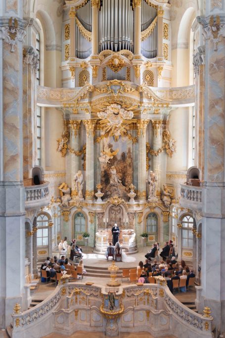 Prunkvolle Kirchenorgel in Frauenkirche Dresden mit barocker Architektur und Musizierenden im Vordergrund.