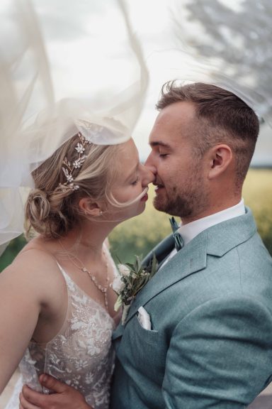 Braut und Bräutigam küssen sich liebevoll vor einer romantischen Kulisse im Freien.